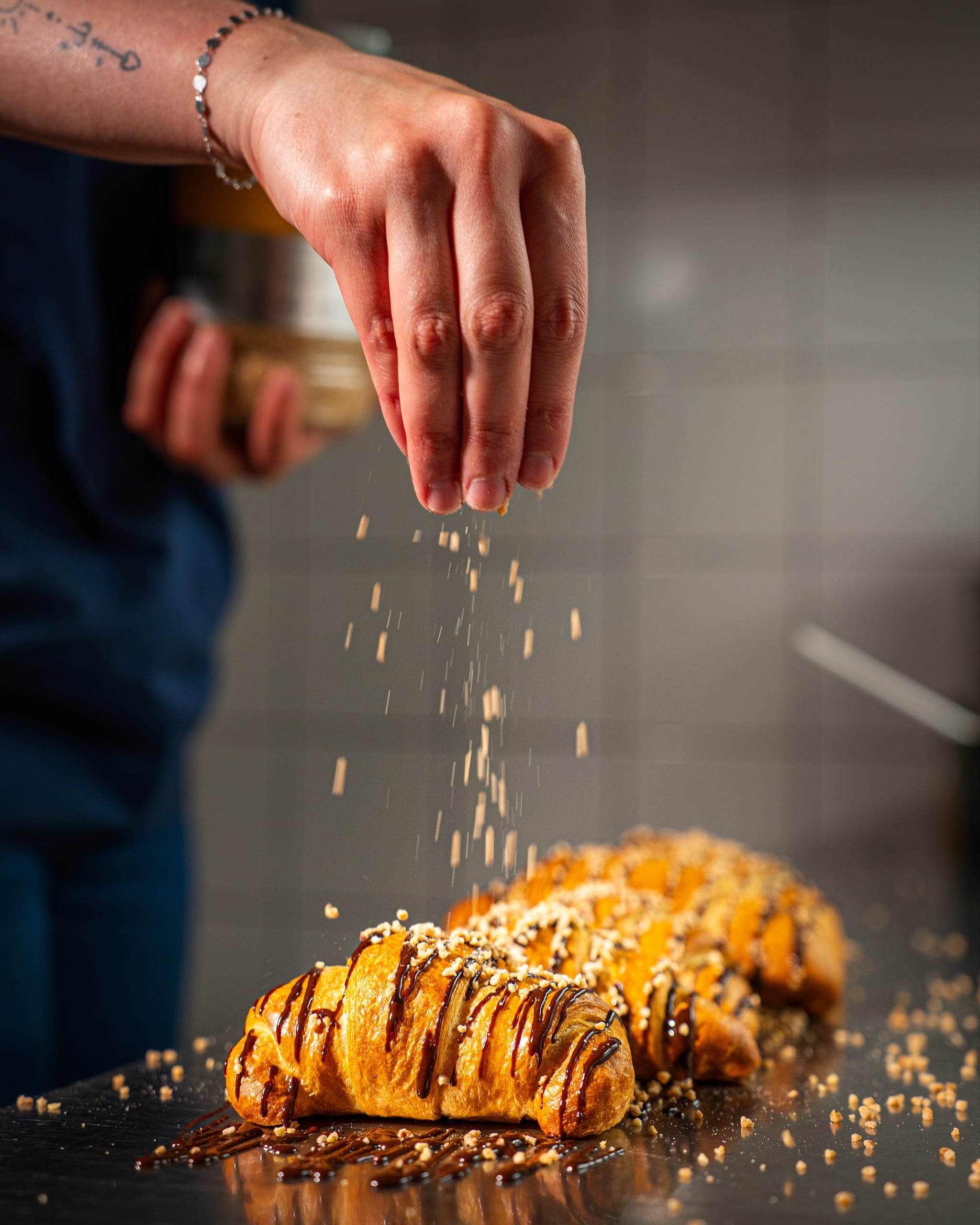 Hand sprinkling crumbs over a glazed pastry