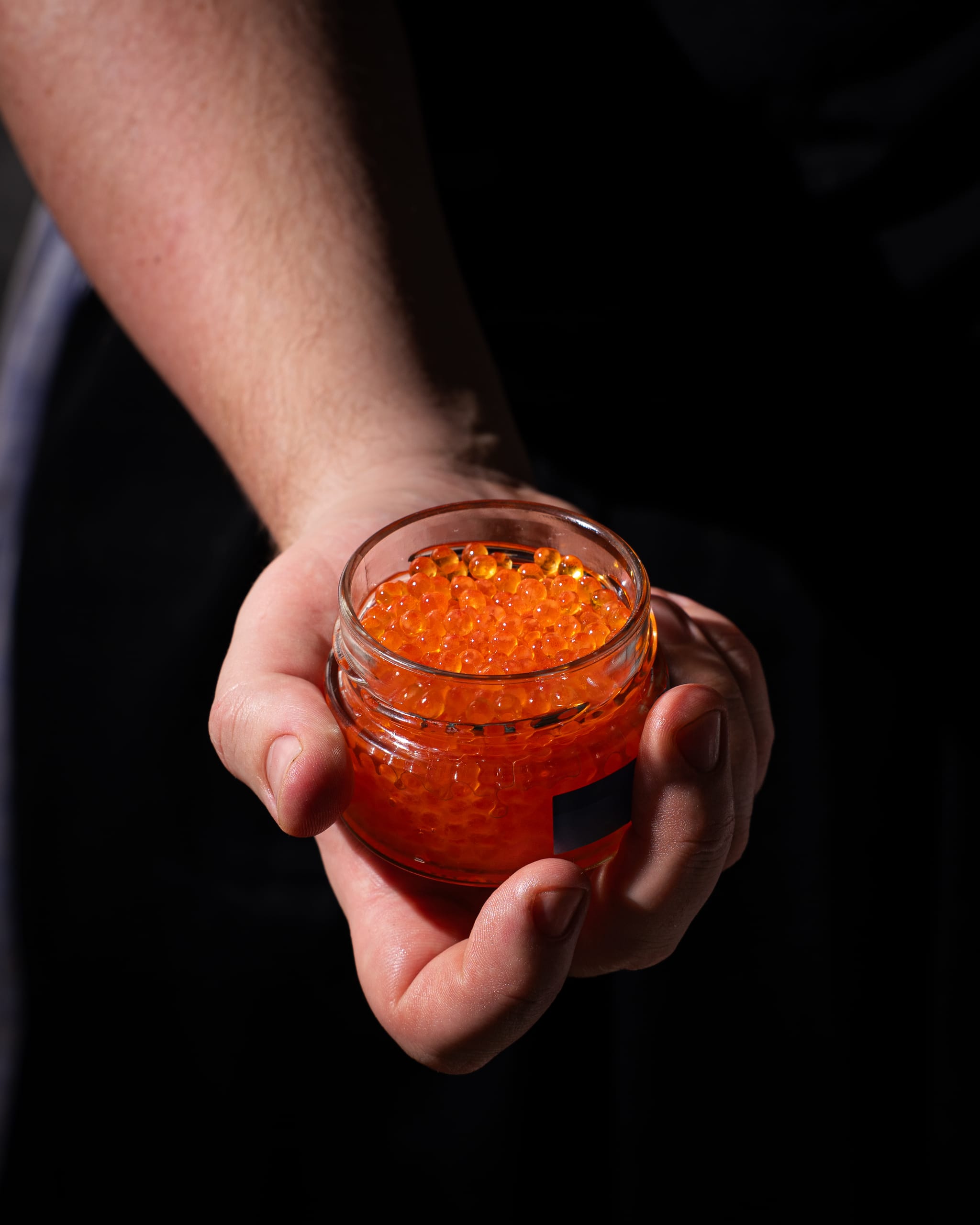 Hand holding a jar of salmon roe