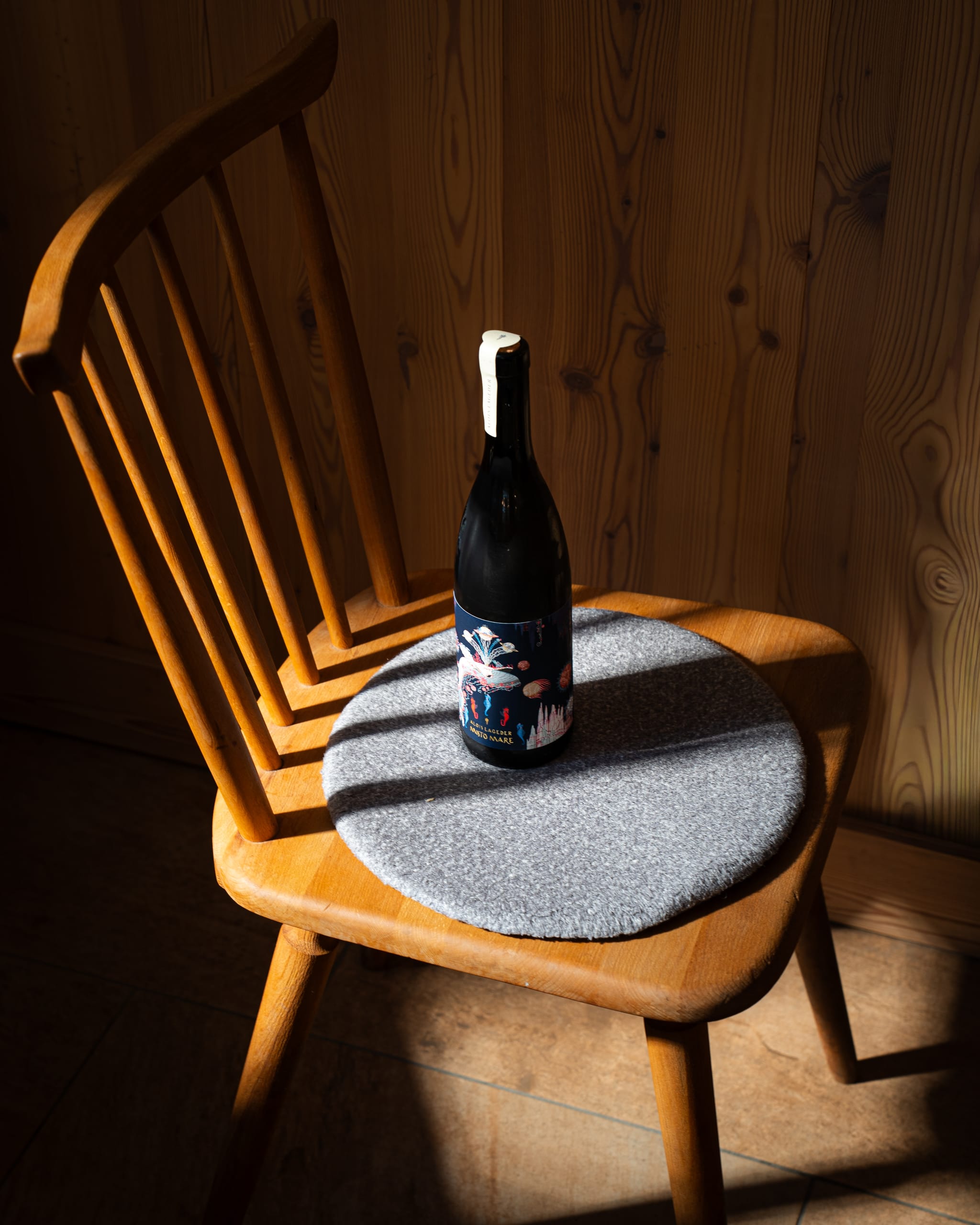 Wine bottle on a wooden chair in a shaft of light