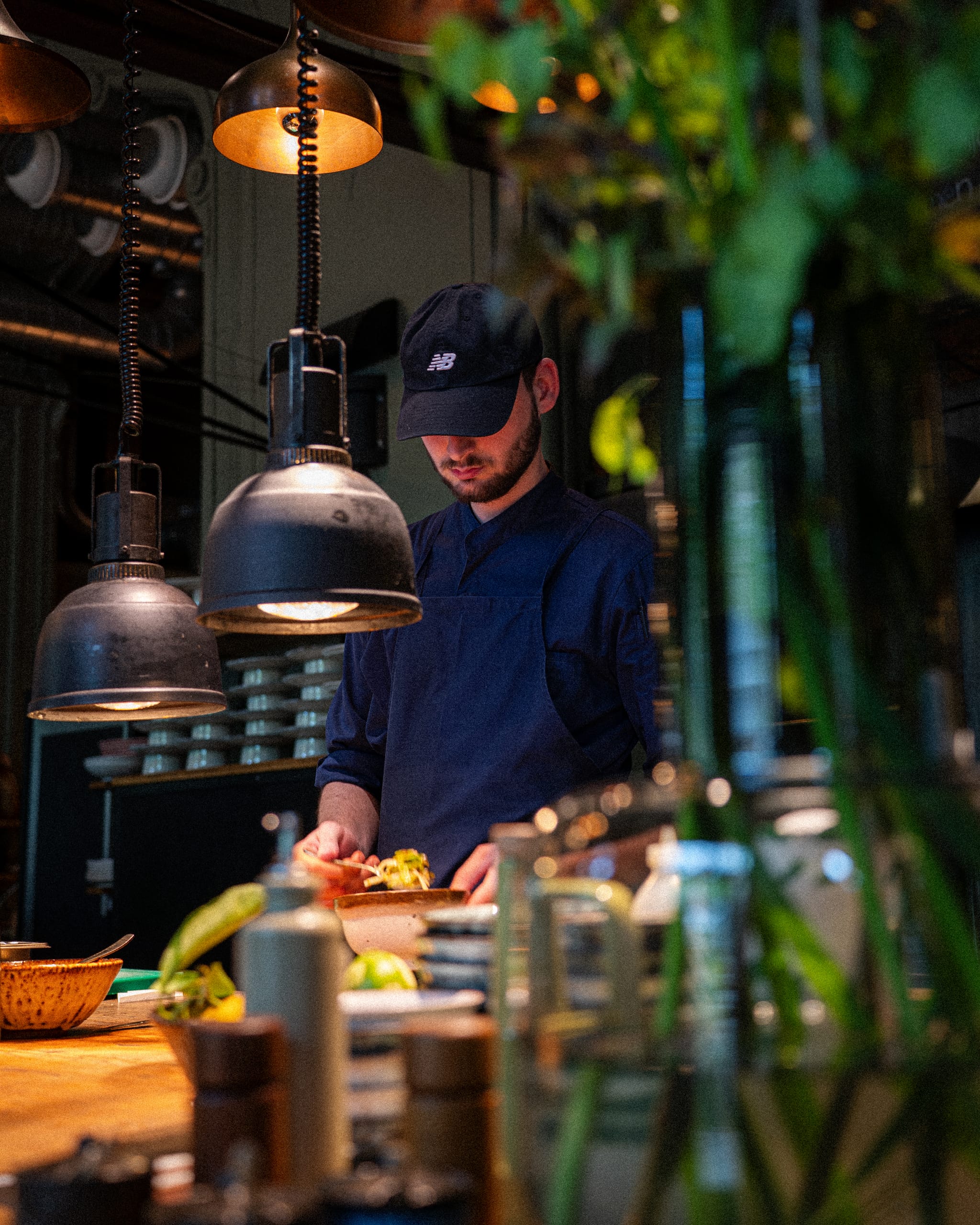 Cook in a cap working under pendant lamps