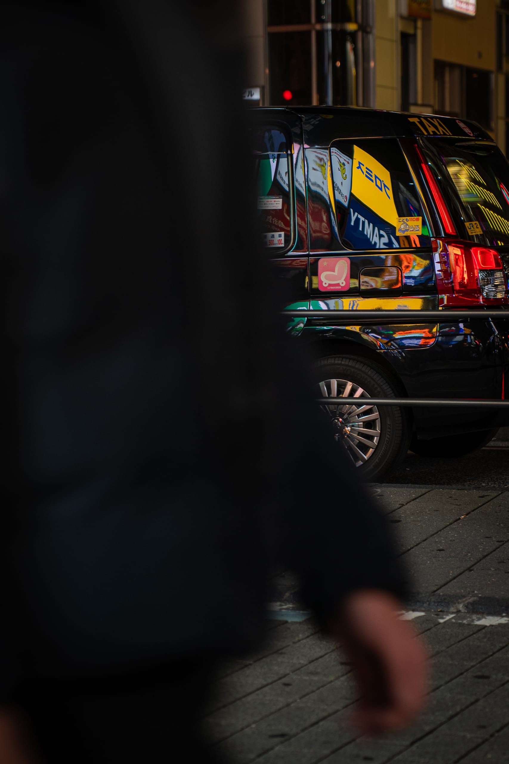Passer-by in shadow beside a parked car