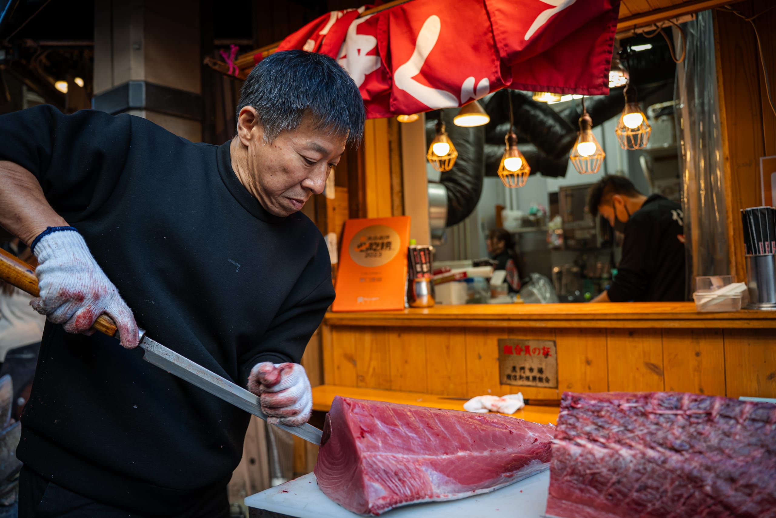 Fishmonger cutting a tuna loin with a long knife