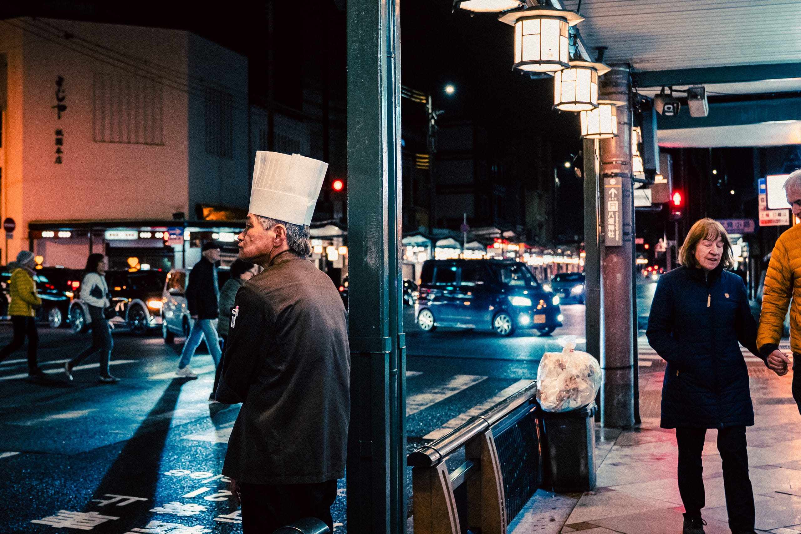 Chef in a toque on a rainy evening street