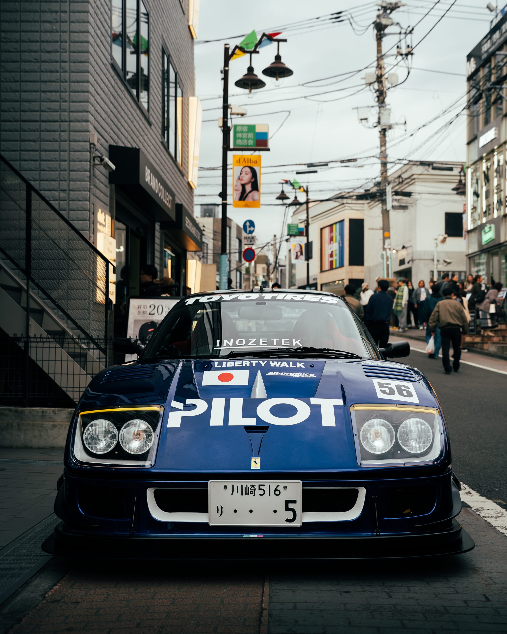 Blue race car in Pilot livery on a narrow street