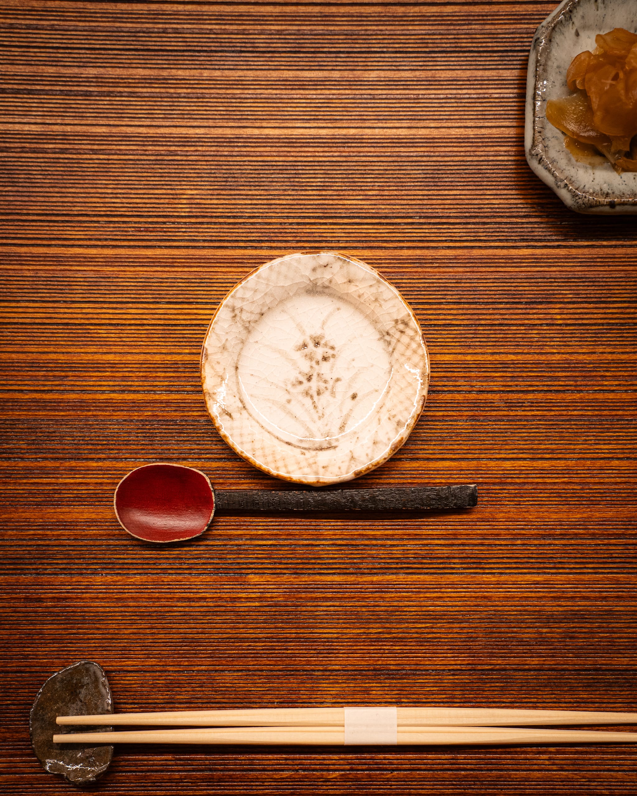 Ceramic plate and chopsticks on a wooden counter, from above