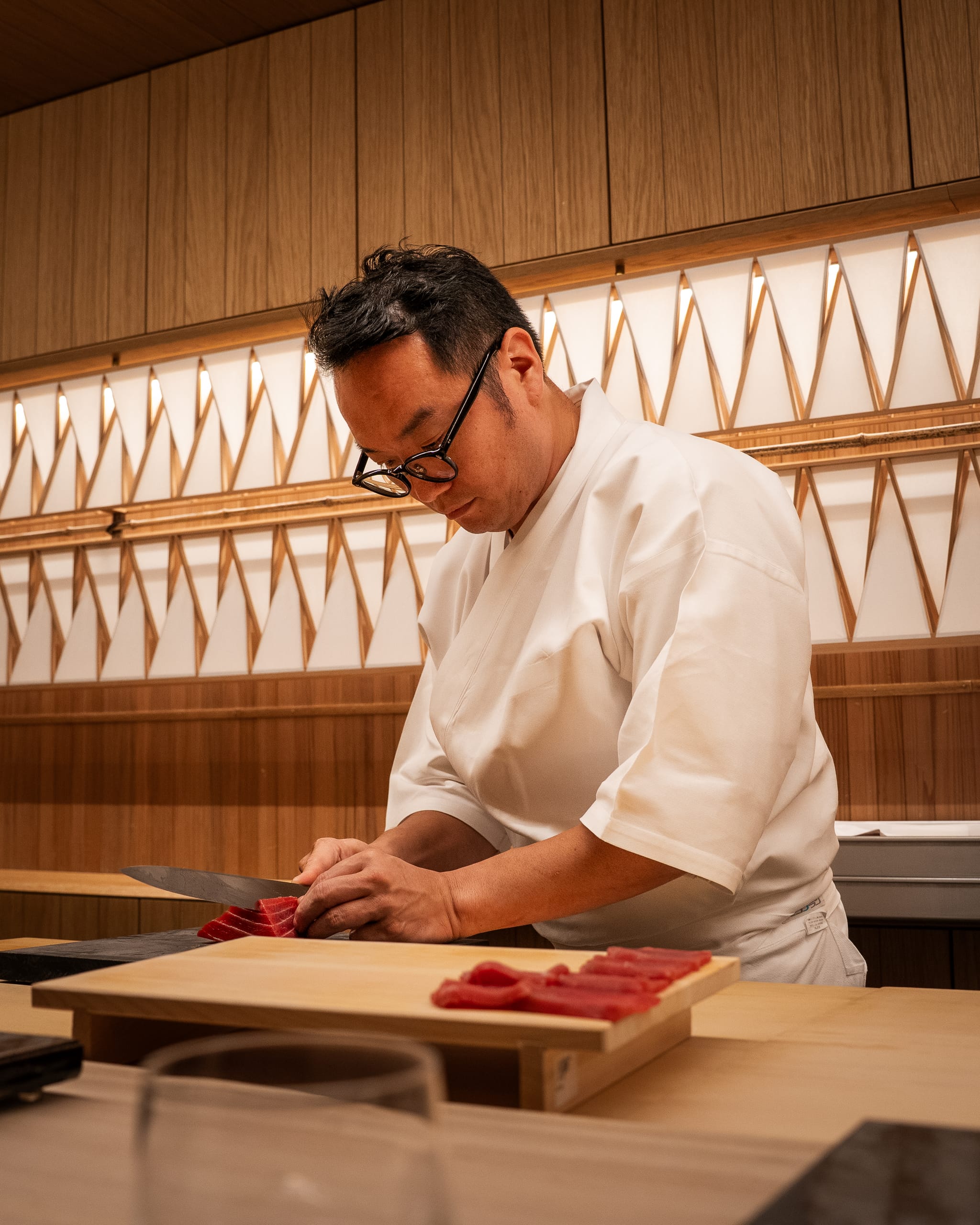 Sushi chef slicing fish at a counter