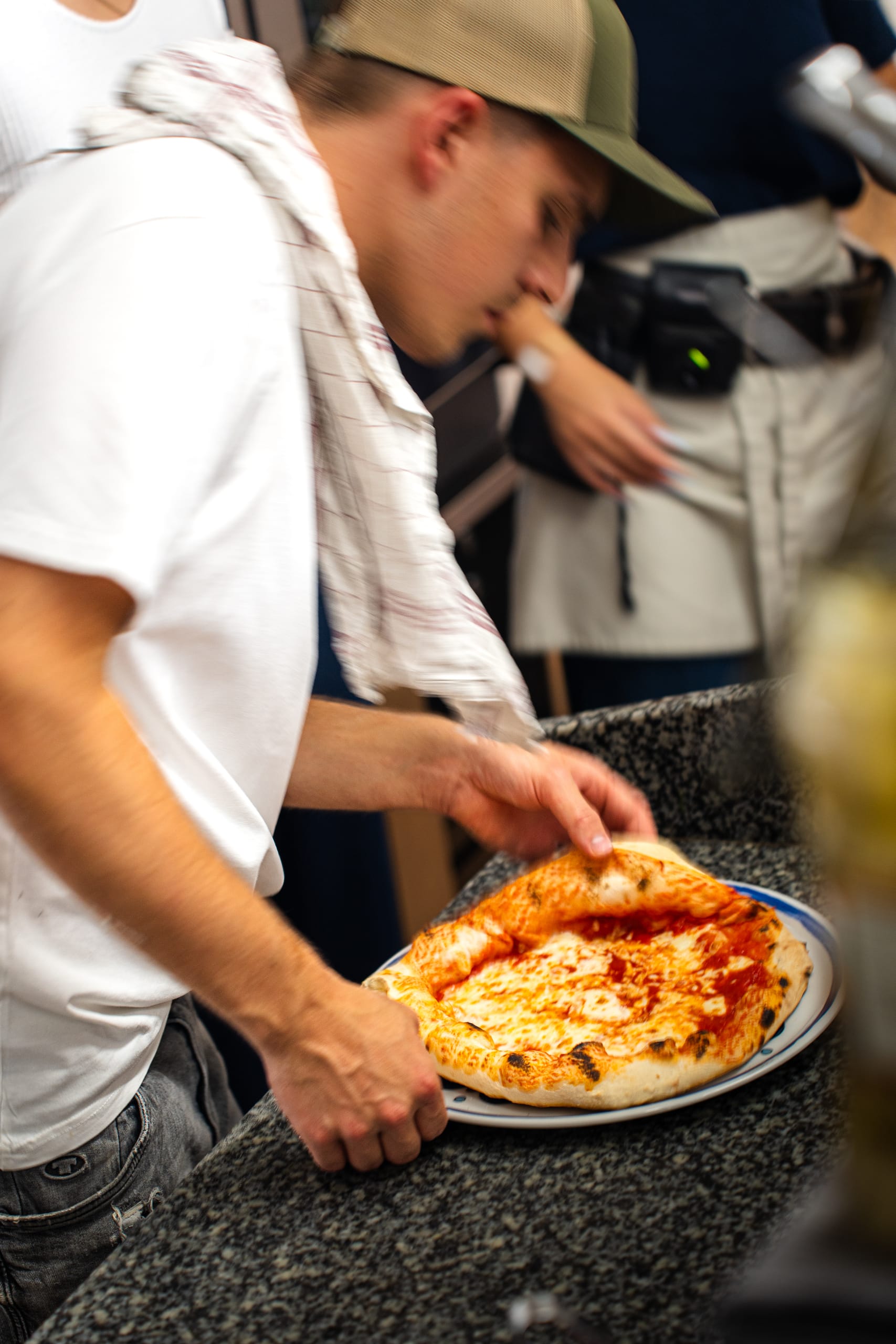 Pizzaiolo in a cap finishing a pizza