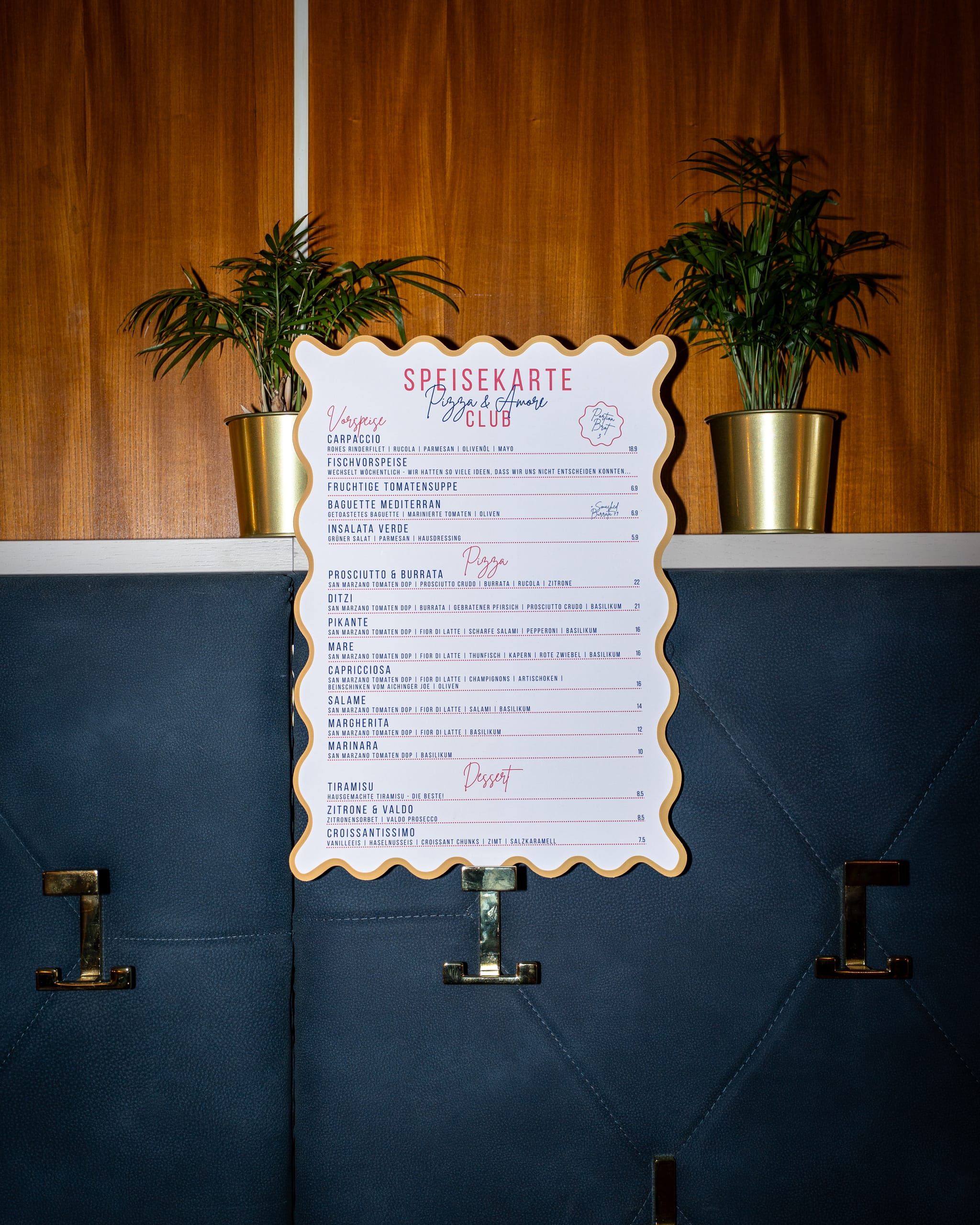 Menu card on a blue wall between potted palms