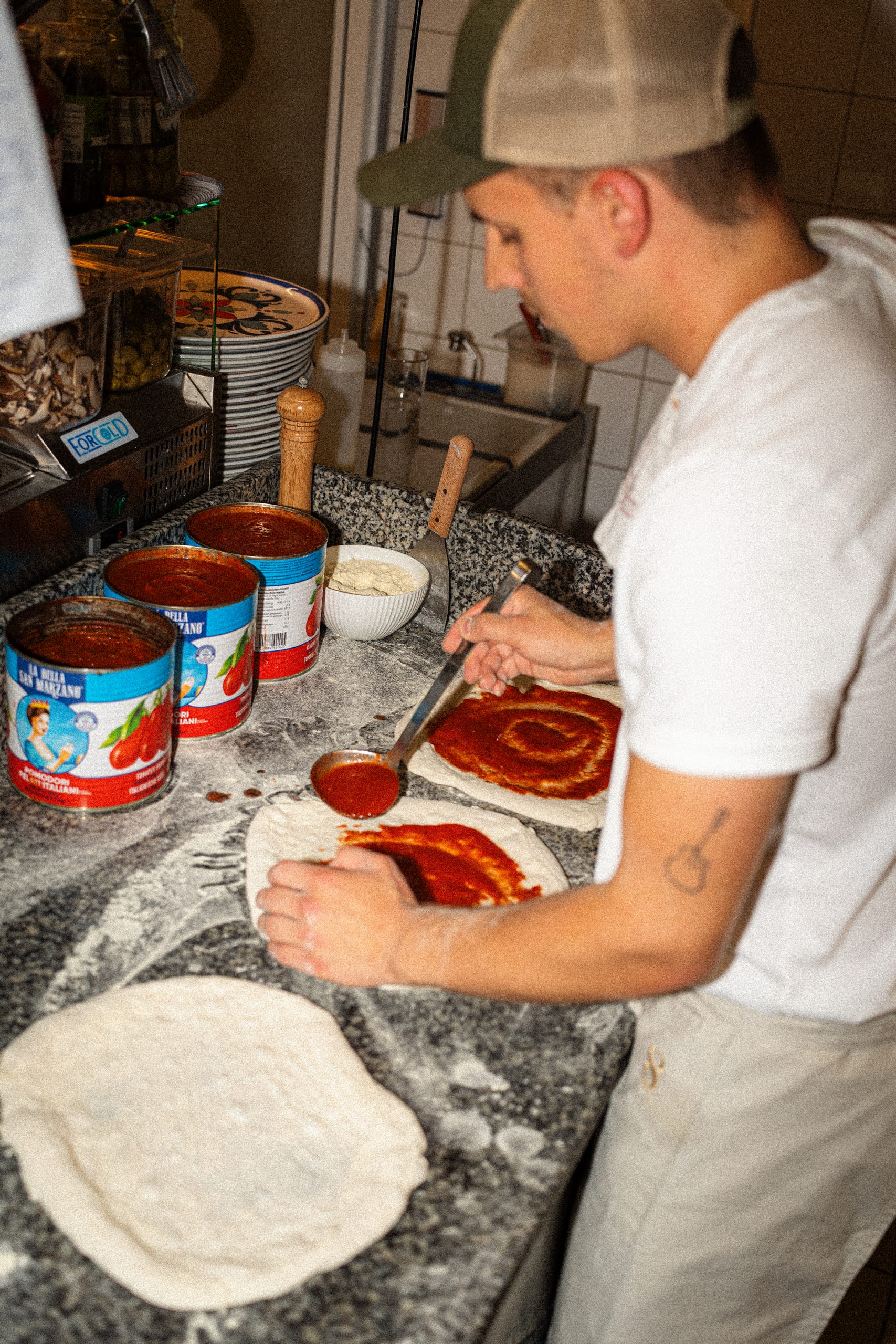 Pizzaiolo spreading tomato over a base
