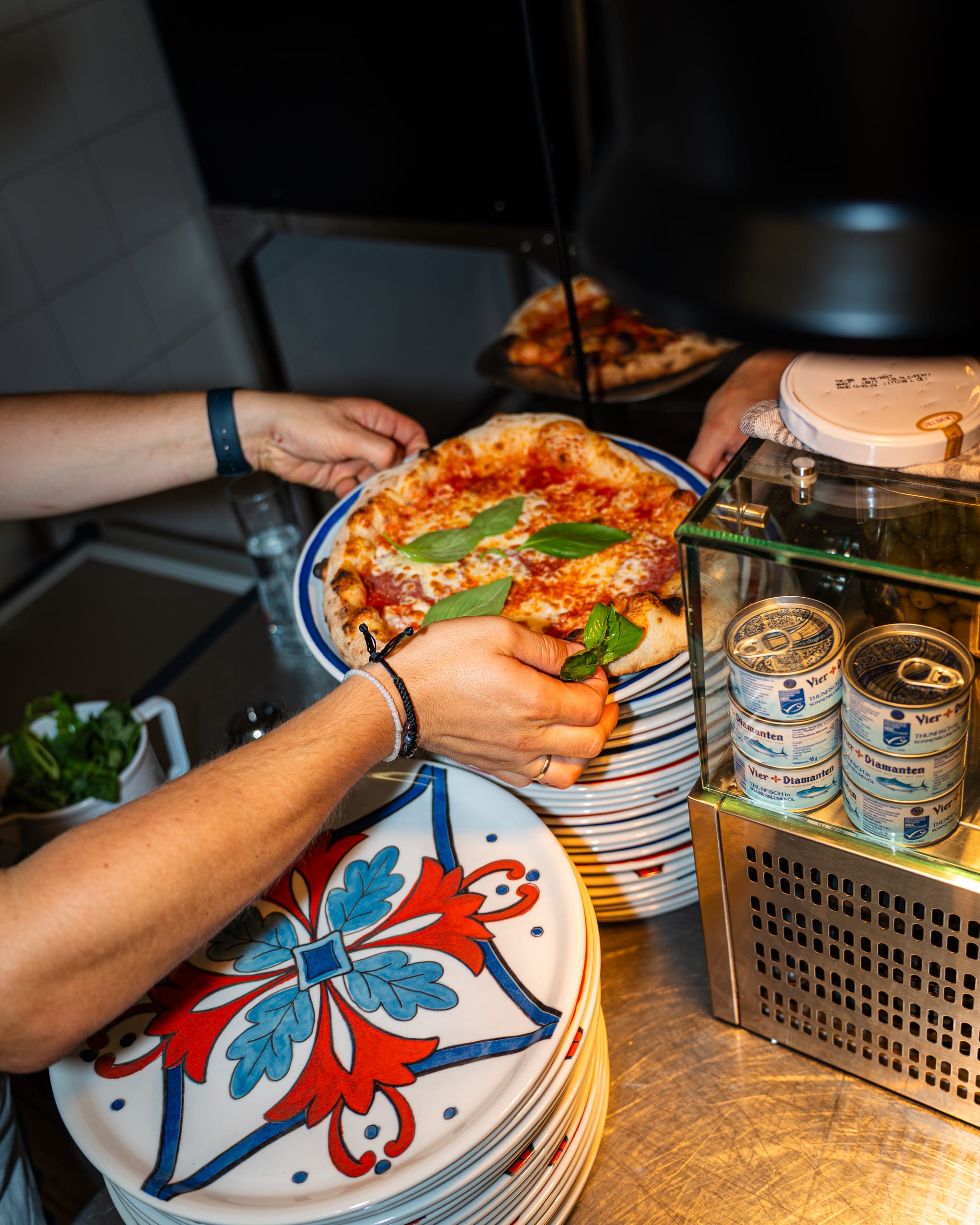 Hands reaching for pizzas on painted plates