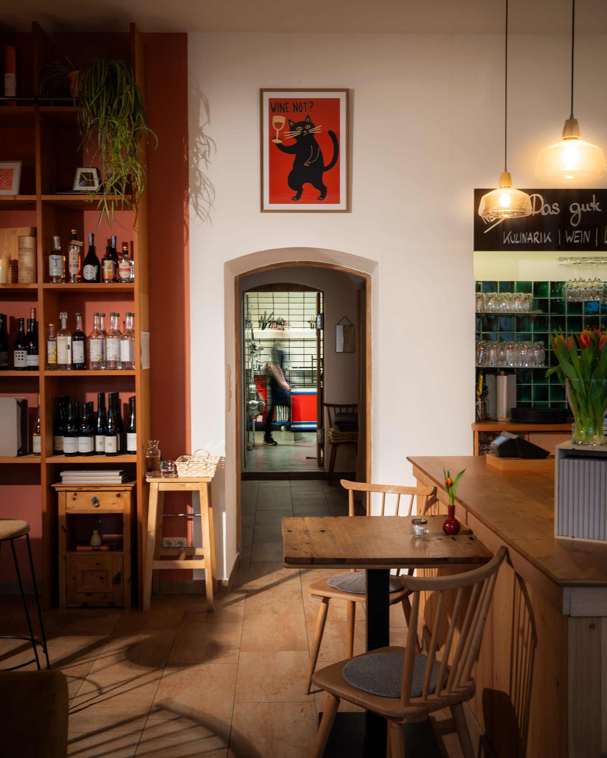 Café interior with wine shelves and an open doorway