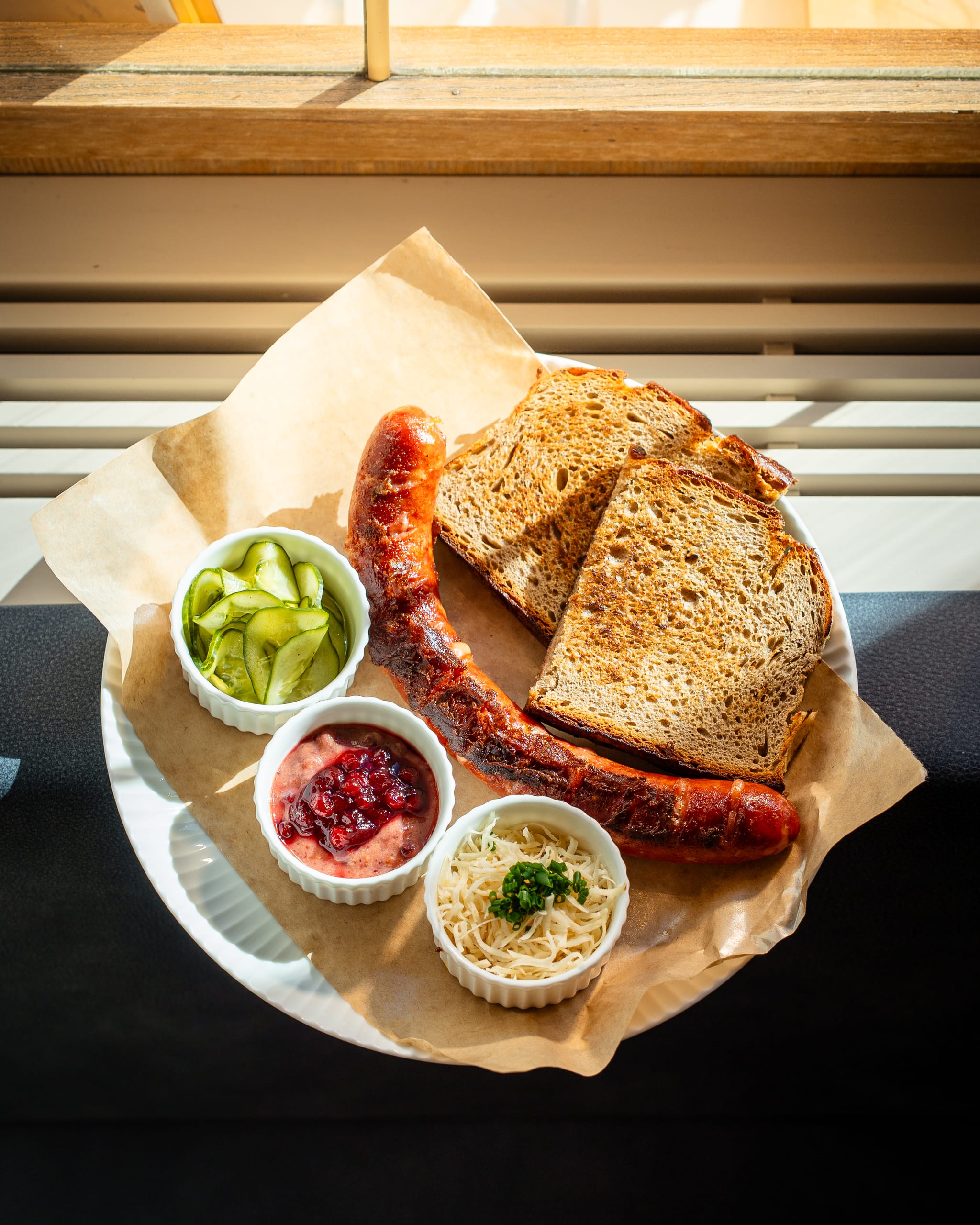 Sausage, bread and dips on a paper-lined plate